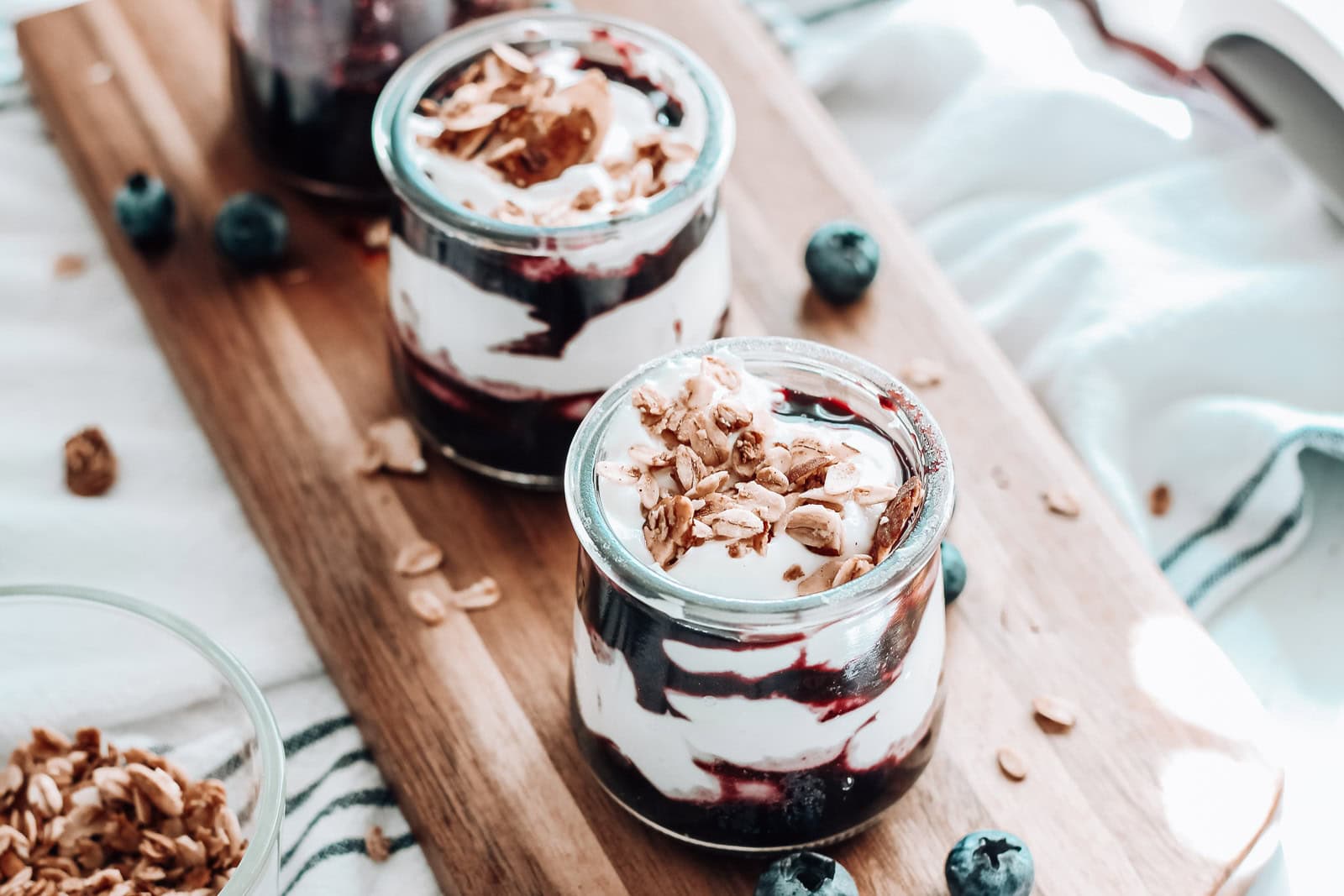 Two blueberry parfaits on a serving board. 