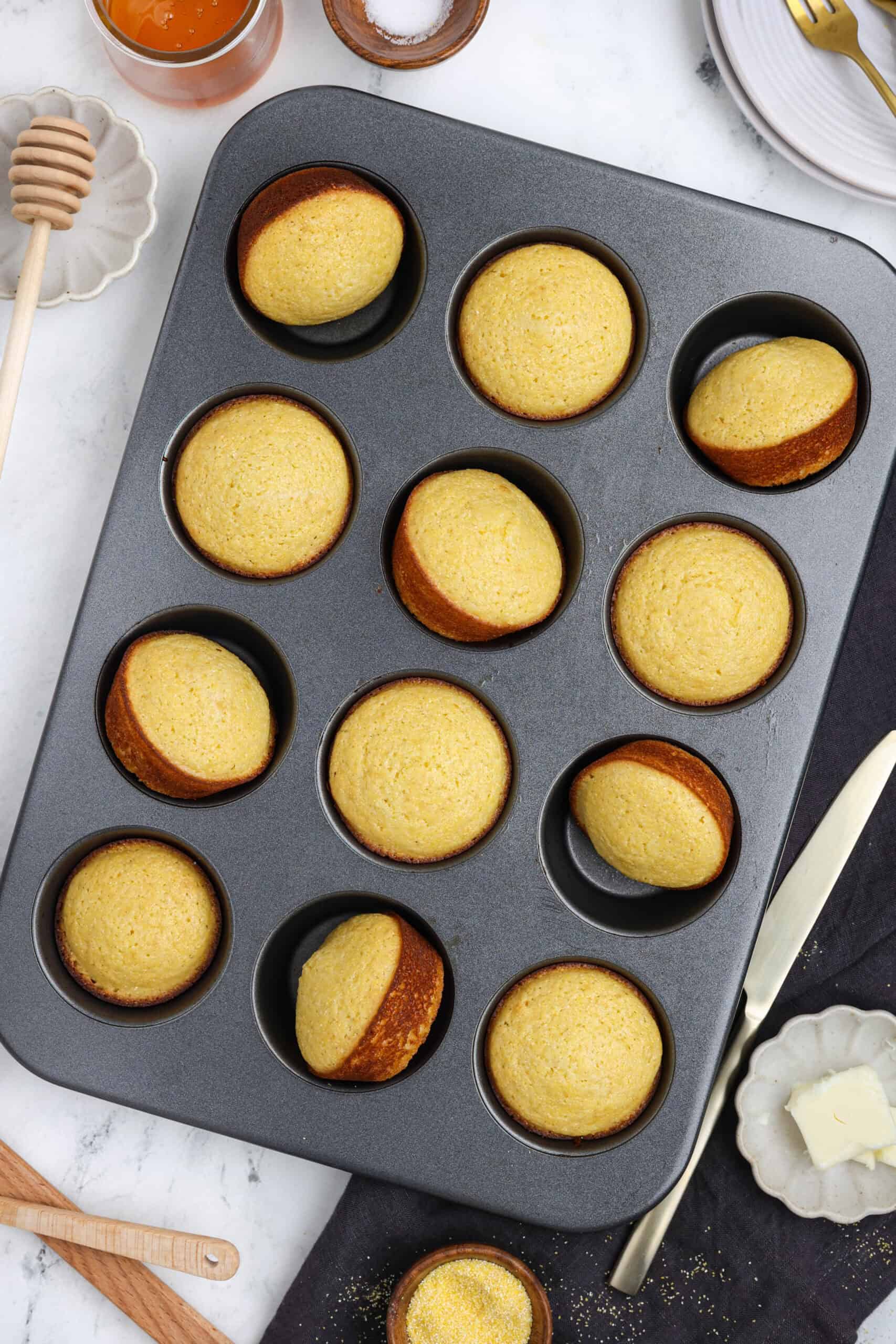 Freshly baked cornbread muffins in a muffin tin.