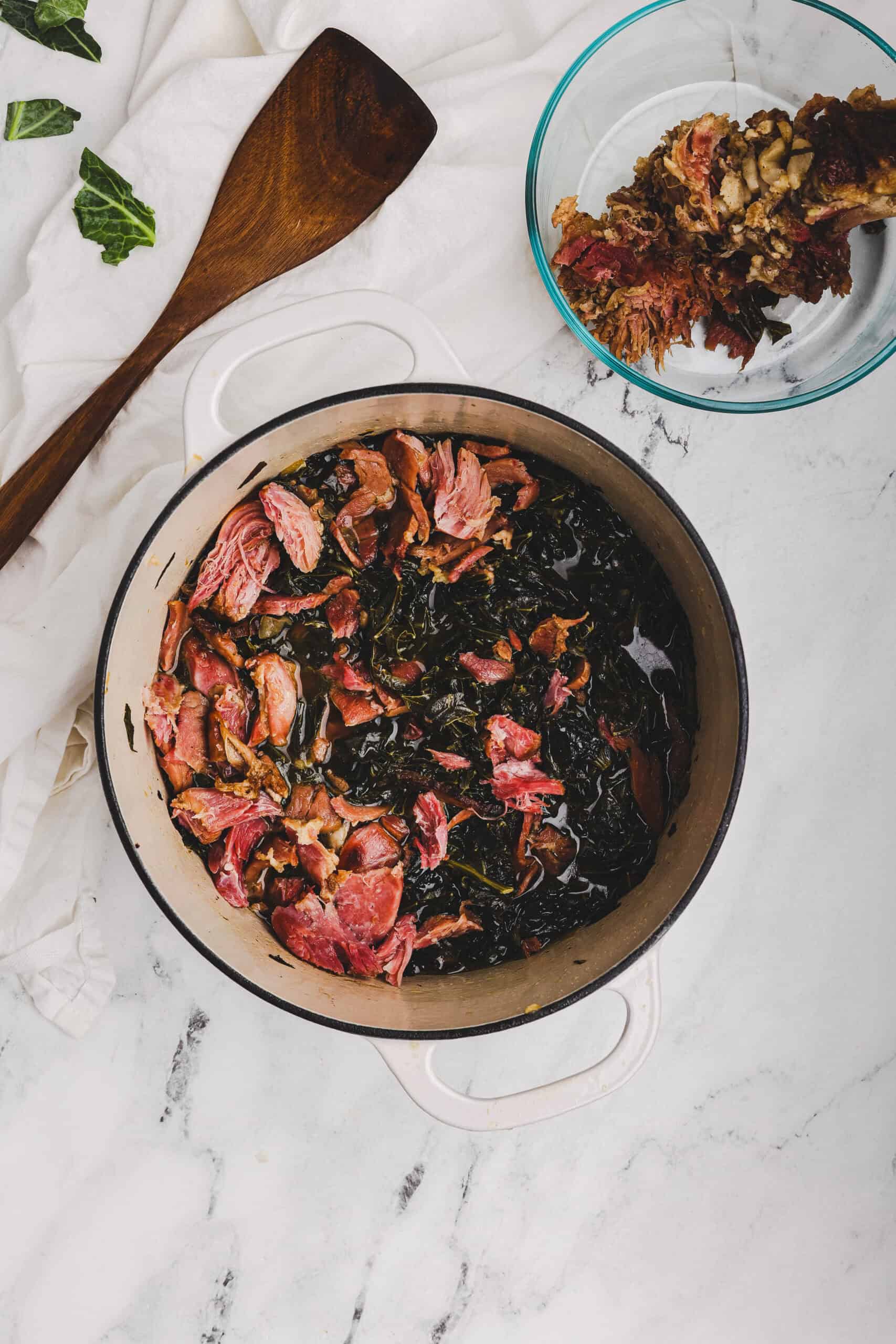Collard greens simmering with ham in seasoned broth.